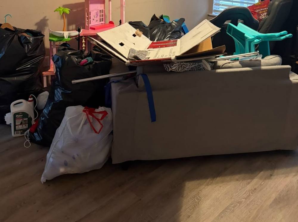 Living room piled with furniture and bagged junk before removal in the Omaha metro